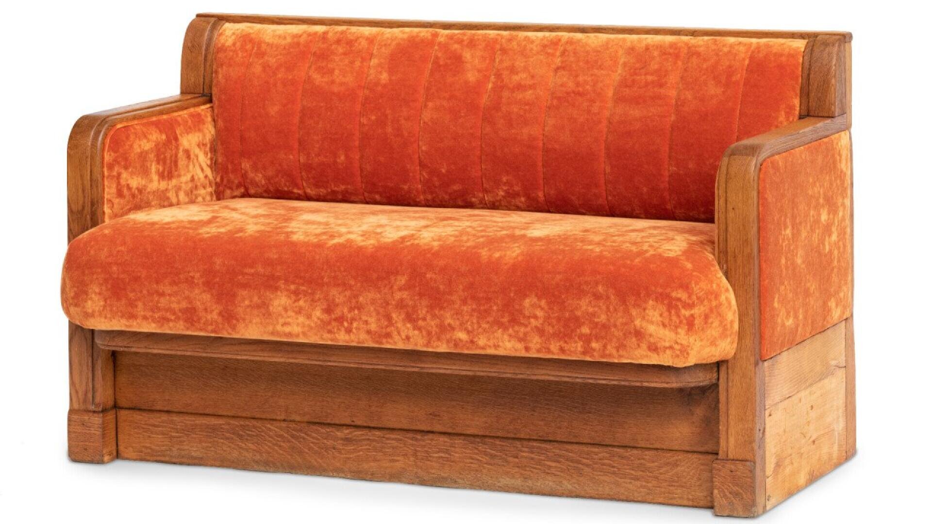 Banc vintage en bois avec accoudoirs rembourrés et revêtement en velours orange sur l'assise et le dossier.