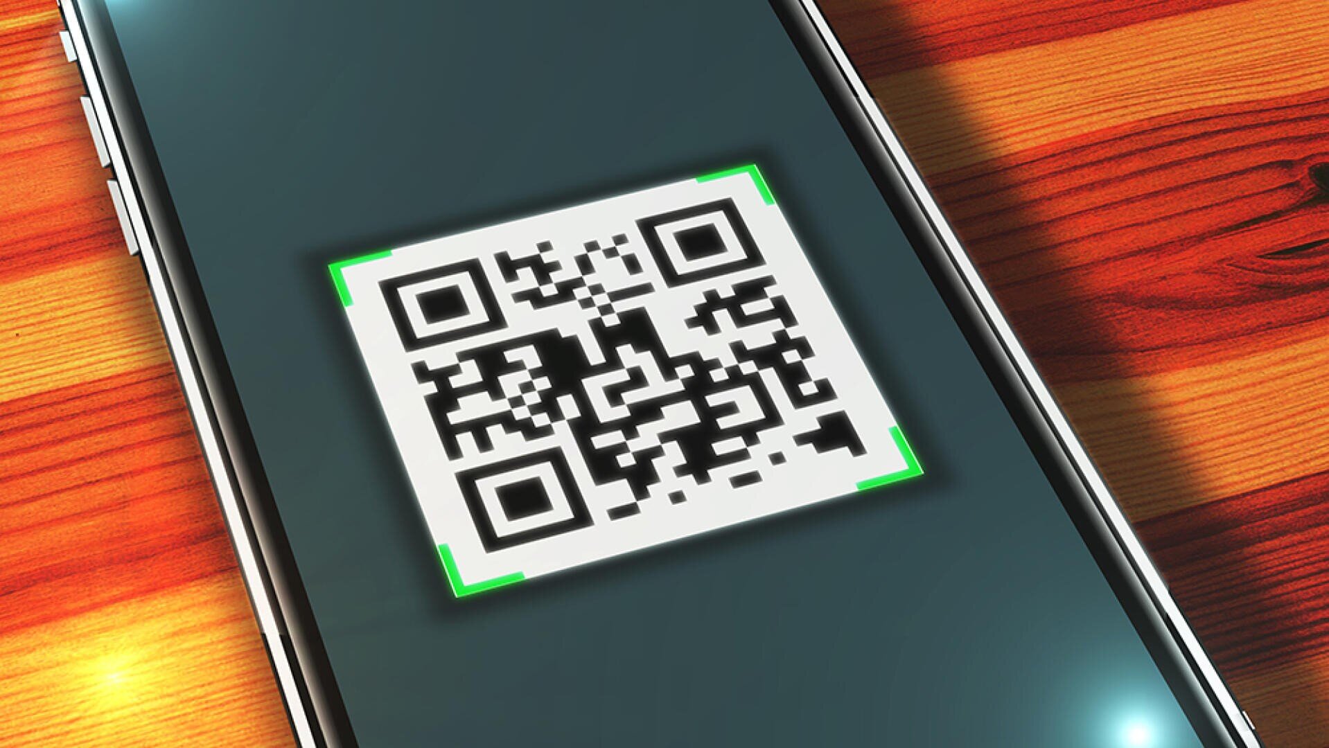L'écran d'un smartphone affiche un code QR en train d'être scanné, avec un contour vert autour du code. Le téléphone repose sur une surface en bois au motif rayé.