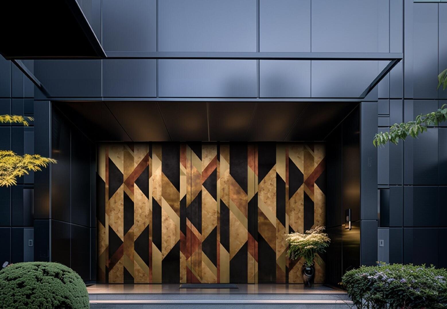 Une entrée de bâtiment moderne avec de grandes portes à motifs géométriques en or, noir et bronze, encadrées par des panneaux métalliques sombres. Des plantes vertes sont placées de chaque côté de l'entrée.