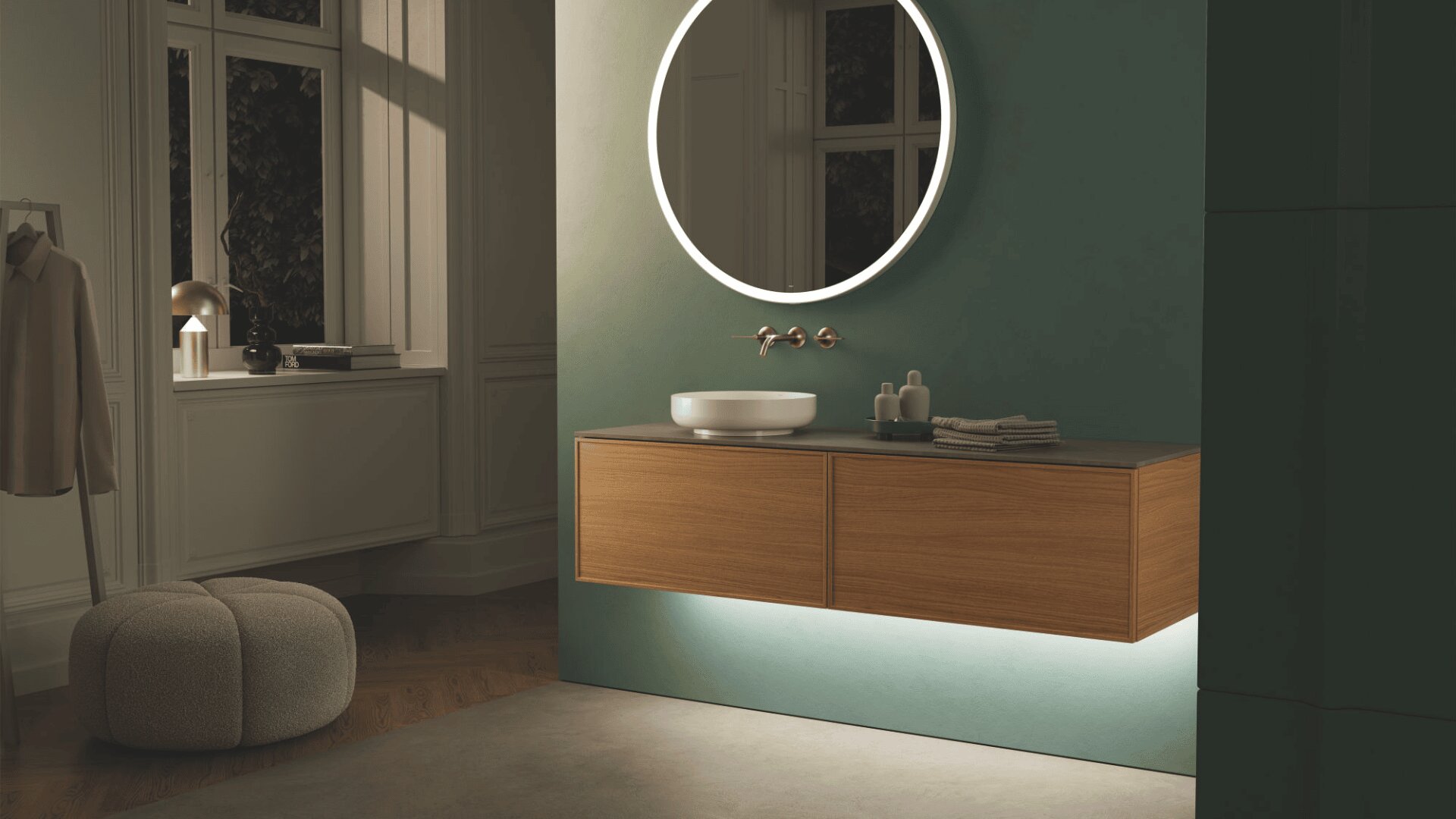 Une salle de bains moderne avec un meuble-lavabo flottant en bois, un lavabo et un robinet mural. Un miroir rond rétroéclairé est suspendu au-dessus. Un éclairage doux et un pouf ottoman créent une atmosphère confortable et minimaliste.