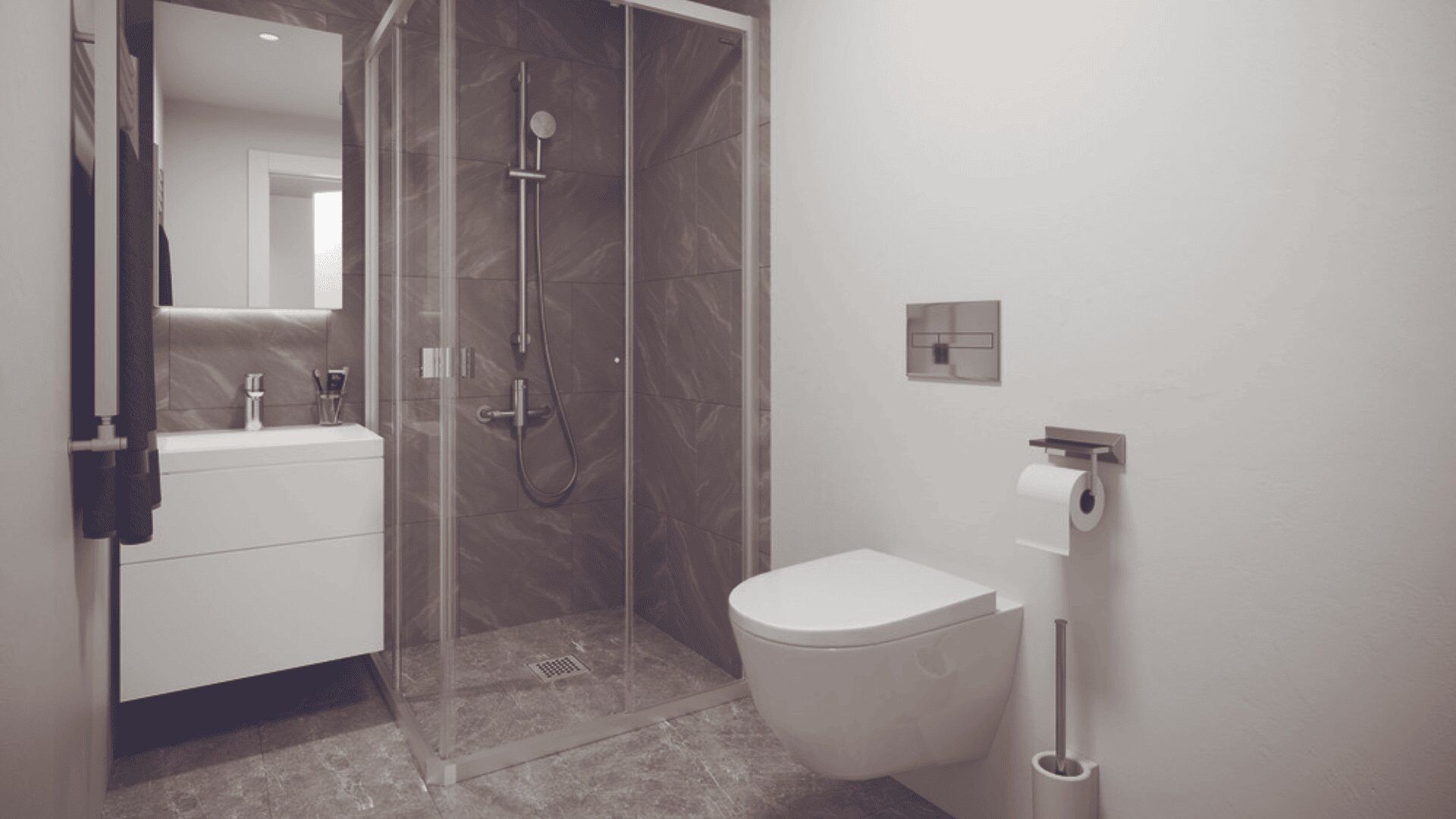 Salle de bains moderne avec douche vitrée, toilettes murales, porte-papier hygiénique et meuble-lavabo blanc surmonté d'un miroir. La douche est équipée de carreaux sombres et d'une pomme de douche à effet pluie.