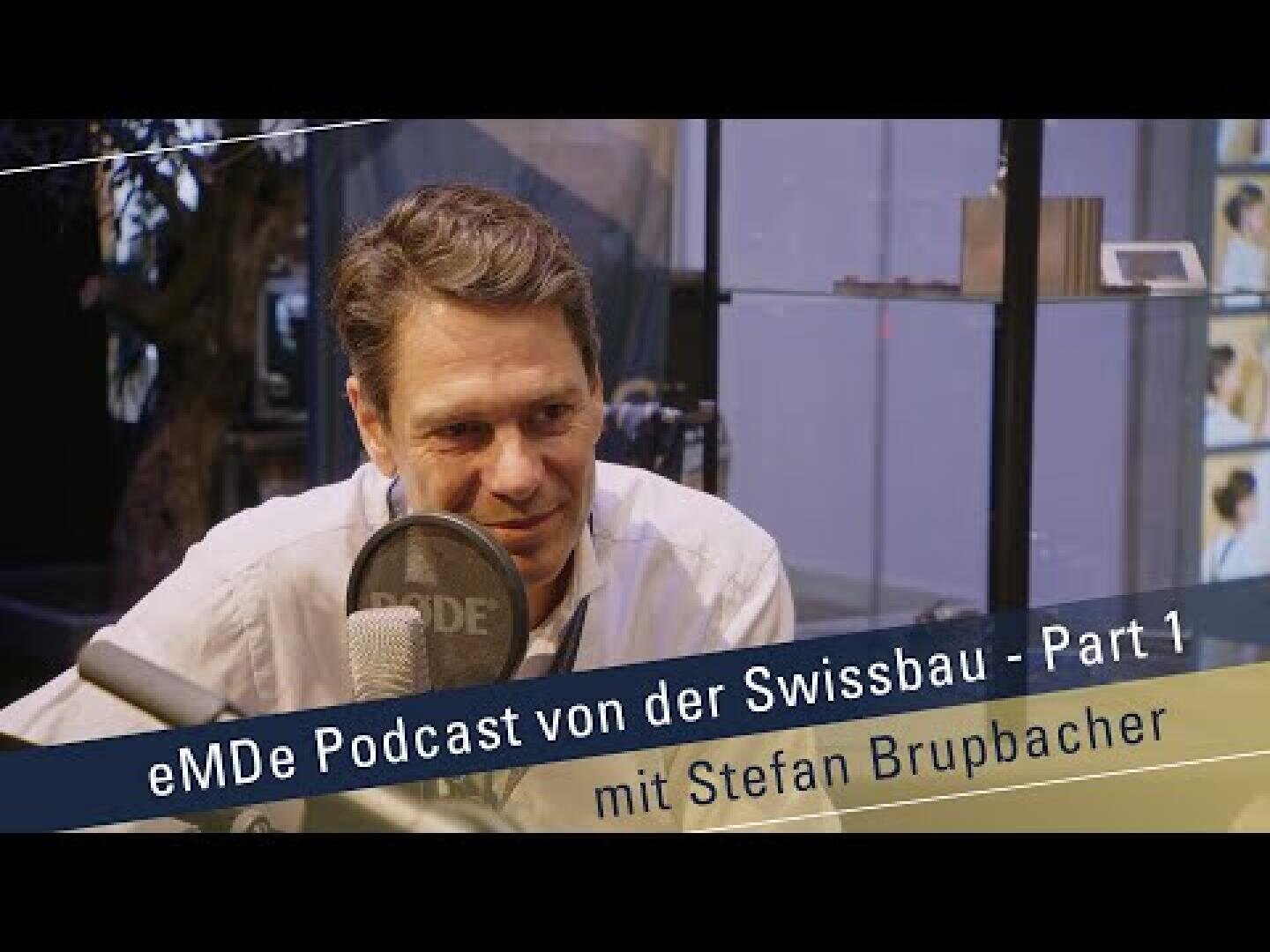 Ein Mann sitzt an einem Mikrofon und spricht während einer Podcast-Aufnahme. Der Text auf dem Bild lautet: eMDe Podcast von der Swissbau - Part 1 mit Stefan Brupbacher.