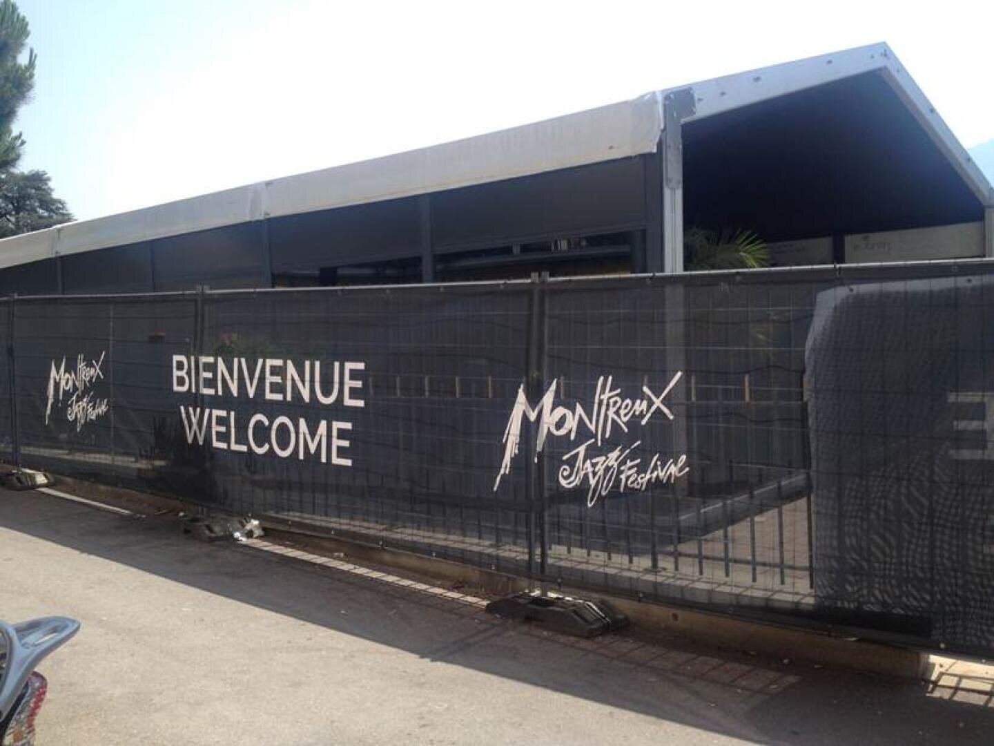 Une grande tente derrière une clôture avec les inscriptions Bienvenue Welcome et Montreux Jazz Festival en lettres blanches sur des bannières noires.