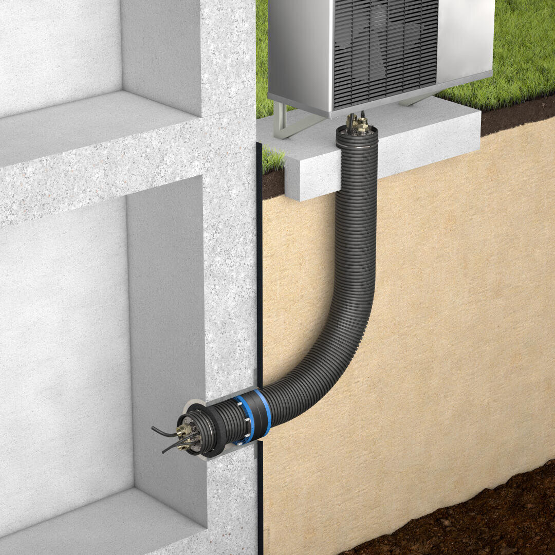 Un tuyau flexible noir relie une unité de chauffage et de ventilation extérieure aux fondations d'un bâtiment et traverse un mur en béton et le sol, les fils étant visibles à l'intérieur du tuyau.