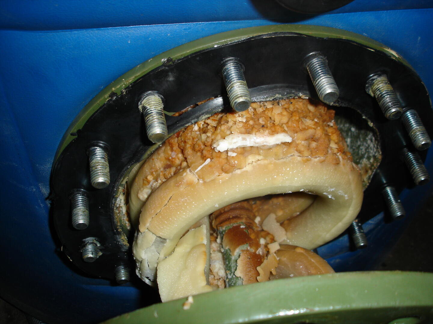 Nahaufnahme eines Maschinenteils mit rundem Flansch und Bolzen, die mit einer dicken, verkrusteten, weißen und braunen Mineralablagerung bedeckt sind, die möglicherweise durch Kesselstein oder Korrosion in Industrieanlagen entstanden ist.