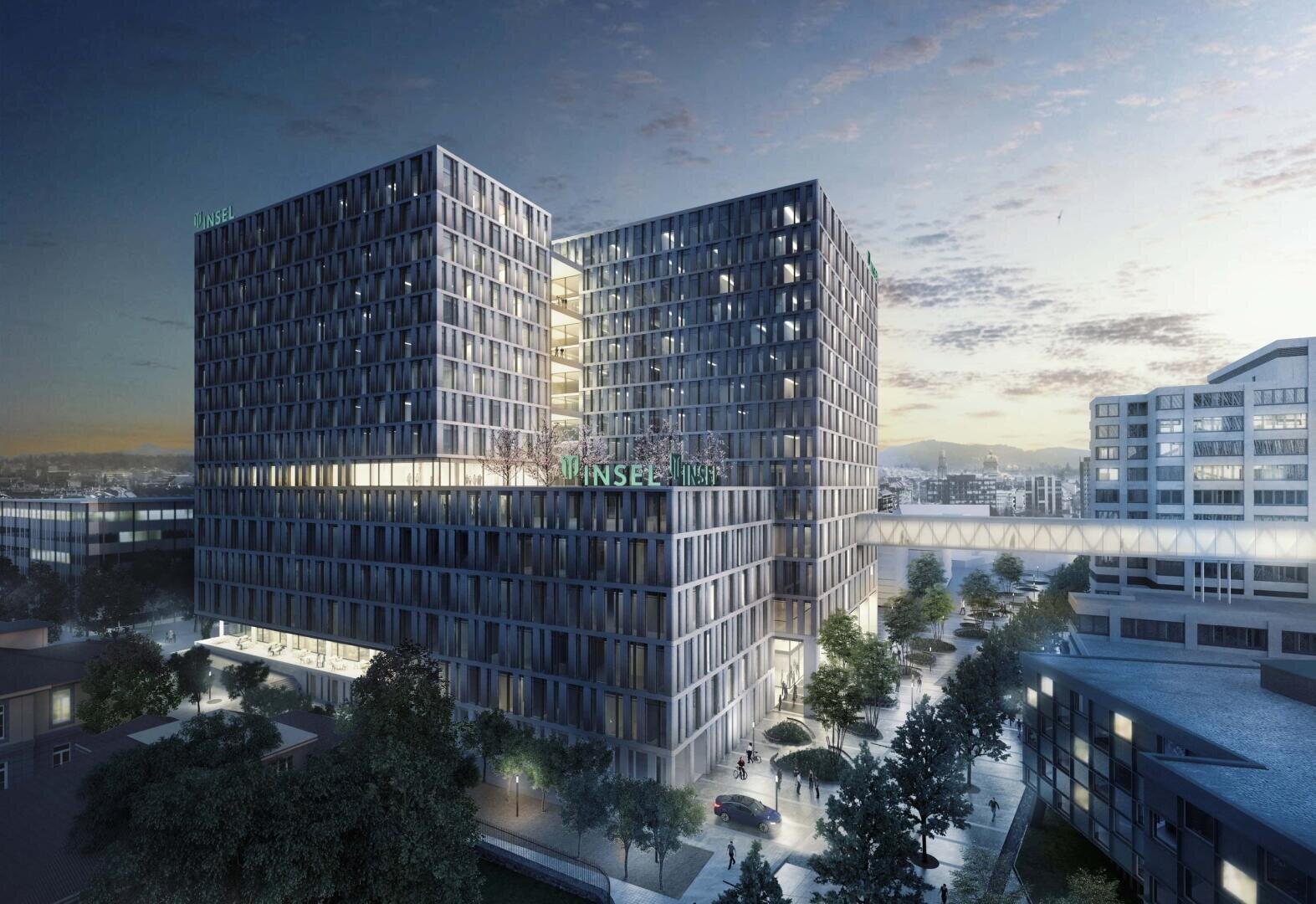Ein modernes, mehrstöckiges Krankenhausgebäude mit großen Glasfenstern ist durch eine Skybridge verbunden. Auf dem Dach ist das Zeichen INSEL beleuchtet. In der Abenddämmerung säumen Bäume und Autos die Straßen darunter.