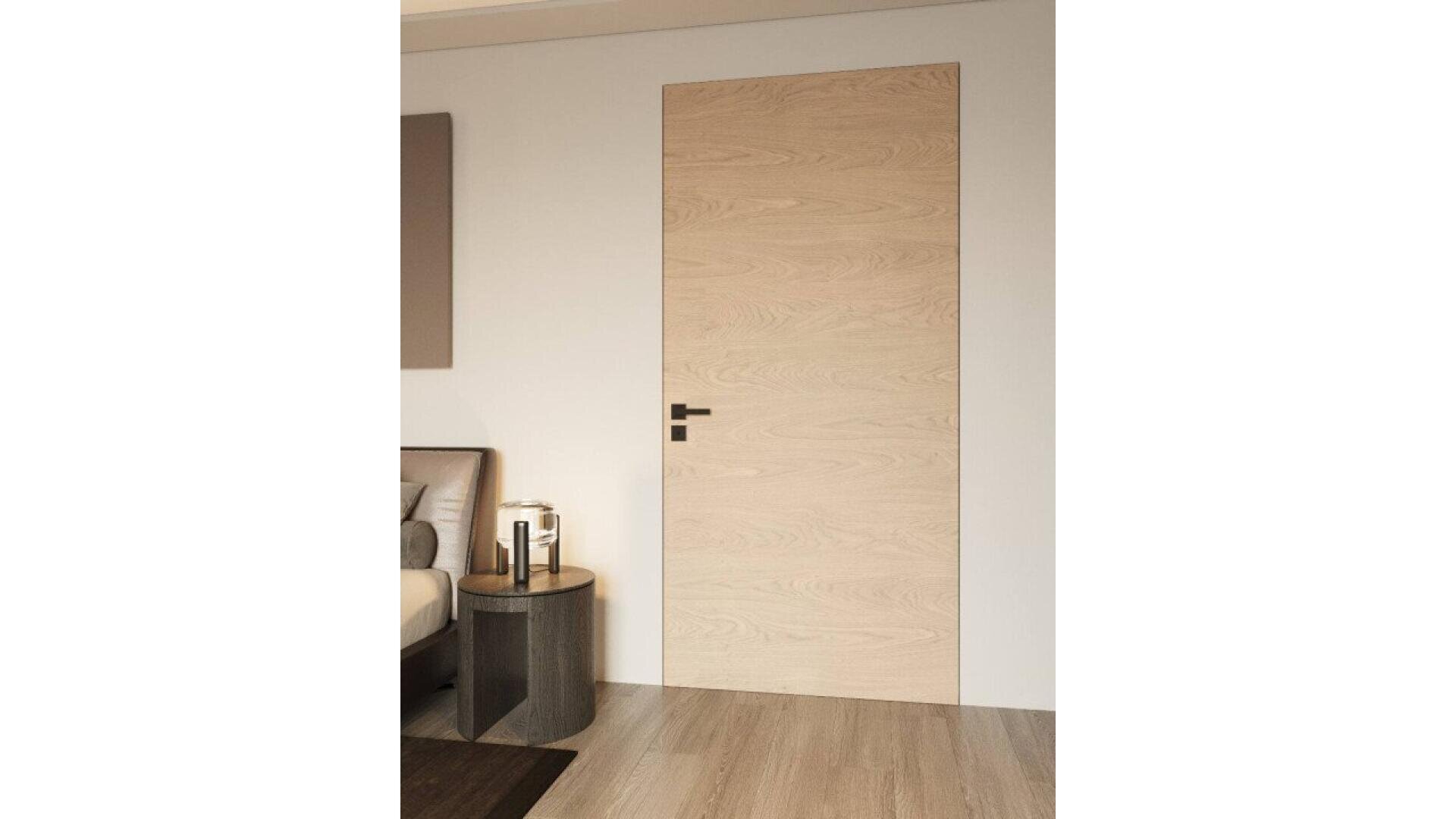 Une porte en bois clair affleurant, au veinage subtil et à la poignée noire, s'intègre parfaitement dans un mur beige, à côté d'une table d'appoint moderne et d'une partie du lit dans une chambre minimaliste.
