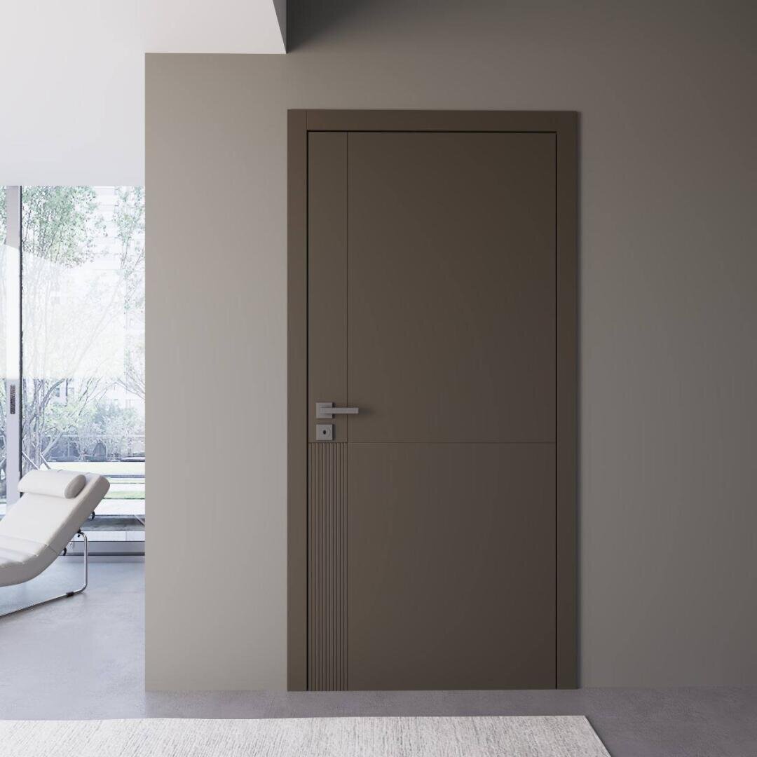 Eine minimalistische braune Tür mit einem modernen Griff ist in eine schlichte Wand eingelassen. Auf der linken Seite lässt ein großes Fenster natürliches Licht herein und gibt den Blick auf einen Teil eines weißen Loungesessels und auf einen Außenbereich mit Bäumen frei.