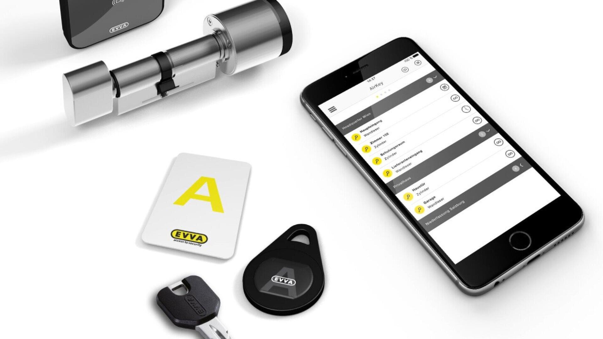 Un smartphone affiche l'interface d'une application de serrure intelligente à côté d'un cylindre de serrure électronique, d'une clé physique, d'une carte clé étiquetée EVVA et d'un porte-clés noir, le tout sur une surface blanche.
