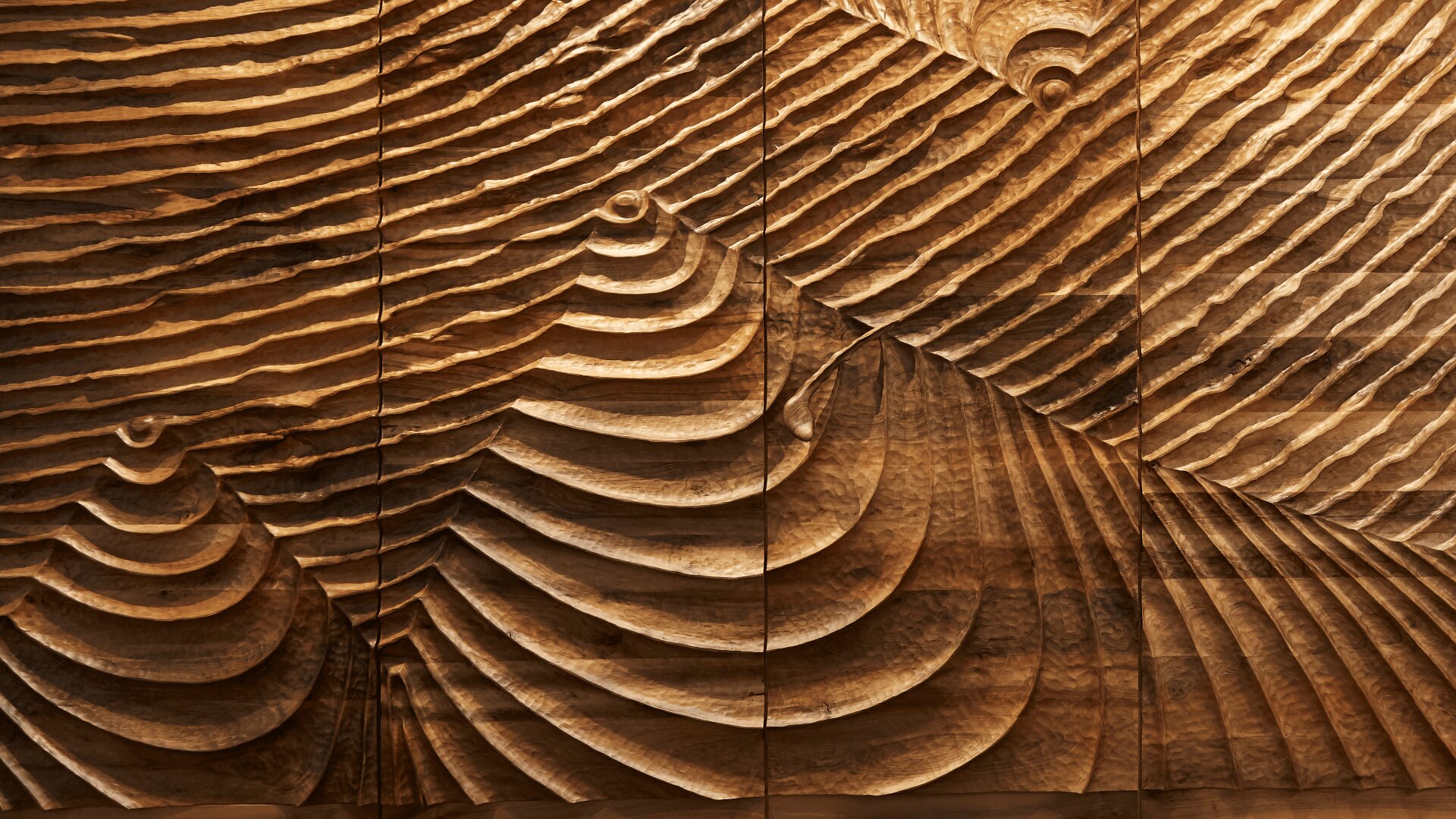 Geschnitzte Wandkunst aus Holz mit geschichteten, gewellten und kreisförmigen Mustern, die eine dreidimensionale, abstrakte Landschaft mit satten Brauntönen und strukturierten Oberflächen schaffen.