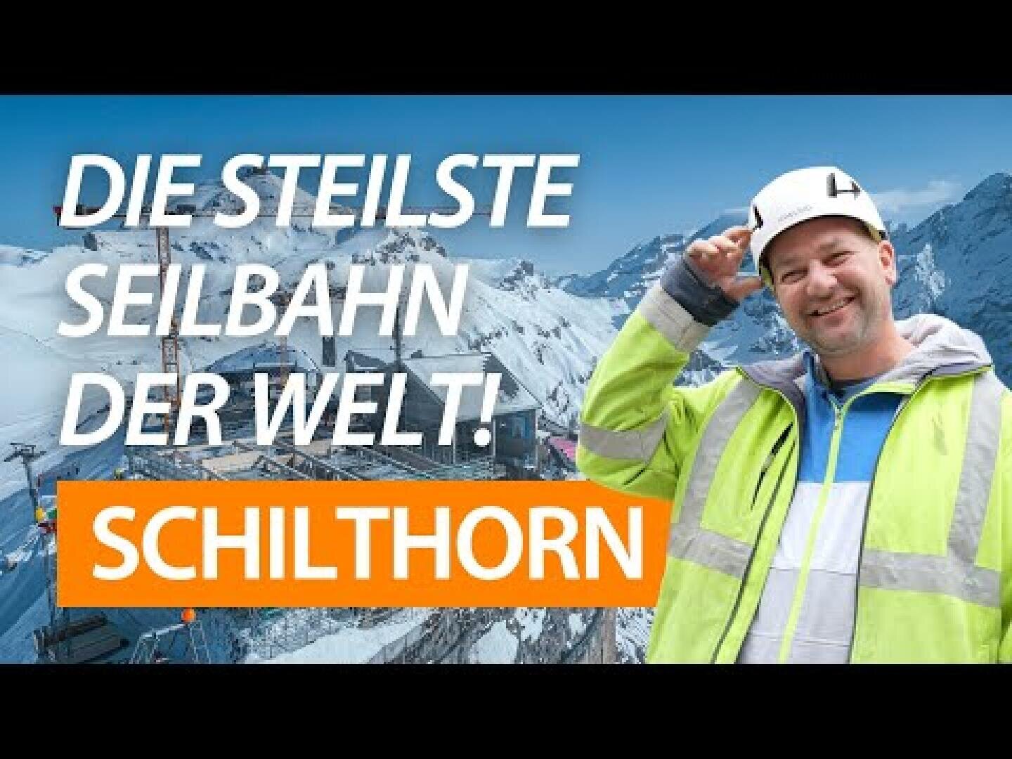 Un ouvrier du bâtiment souriant, portant un casque de protection et une veste réfléchissante, se tient devant des montagnes enneigées et un téléphérique. Le texte dit : "Le téléphérique le plus raide du monde ! Le Schilthorn.