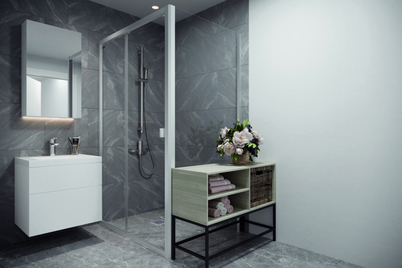 Salle de bains moderne avec carrelage en marbre gris, douche vitrée, meuble-lavabo flottant blanc avec miroir et étagère en bois clair contenant des serviettes, des paniers et une composition florale.