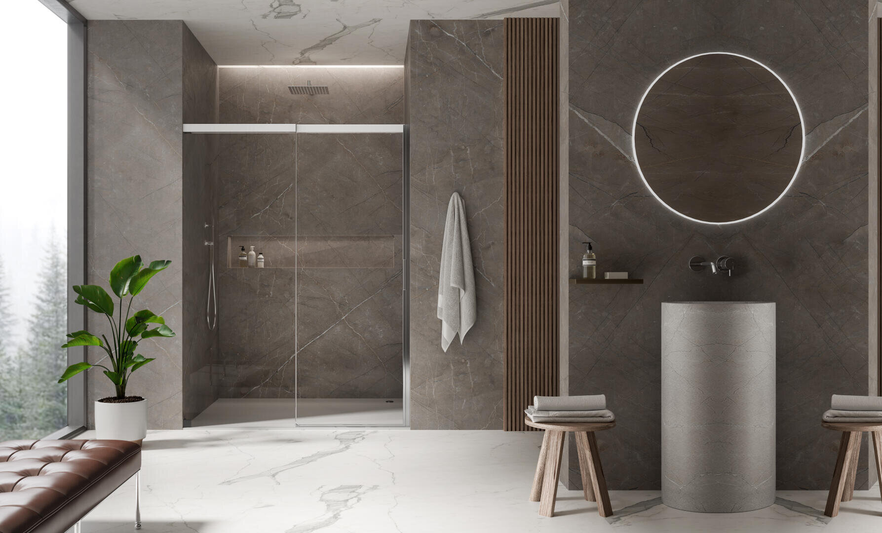 Modernes Badezimmer mit grauen Steinwänden, einer begehbaren Dusche mit Glastüren, einem runden, beleuchteten Spiegel über einem zylindrischen Waschbecken, zwei Hockern, einem Handtuch, einer Topfpflanze und einem Fenster mit Blick auf die Bäume.