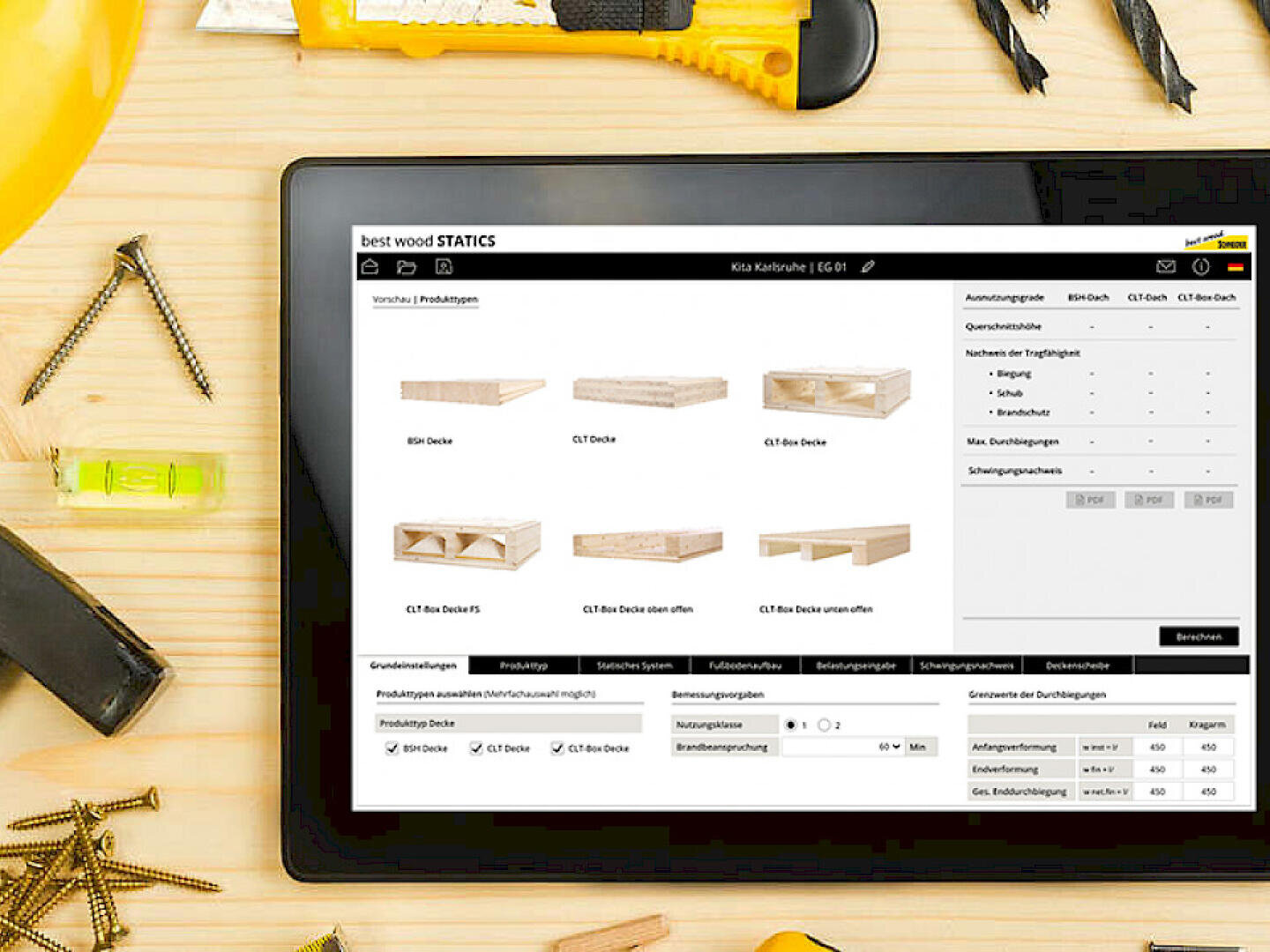 Ein Tablet mit einer Holzbauplanungssoftware steht auf einem Schreibtisch, umgeben von Holzbearbeitungswerkzeugen, Schrauben und Bolzen. Die Software zeigt Bilder und Spezifikationen von verschiedenen Holzbalkenarten.