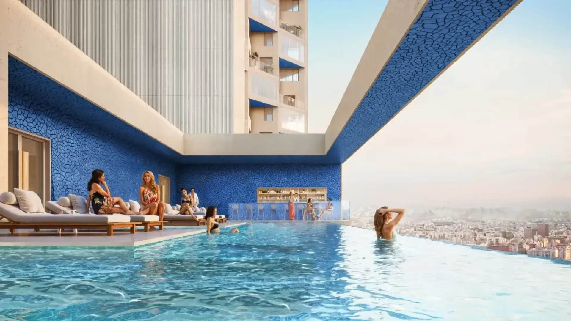 Les gens se détendent au bord d'une piscine à débordement moderne sur le toit, décorée de mosaïques bleues, et regardent un paysage urbain au coucher du soleil. Des chaises longues bordent la piscine et un bar est visible en arrière-plan.