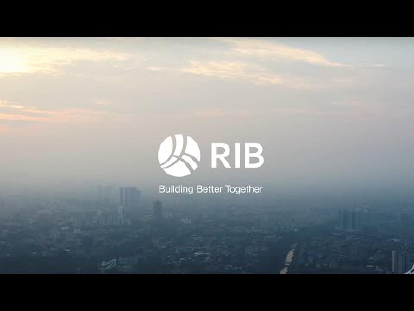 Eine dunstige Stadtlandschaft bei Sonnenaufgang mit dem RIB-Logo in der Mitte und dem darunter stehenden Slogan Building Better Together.