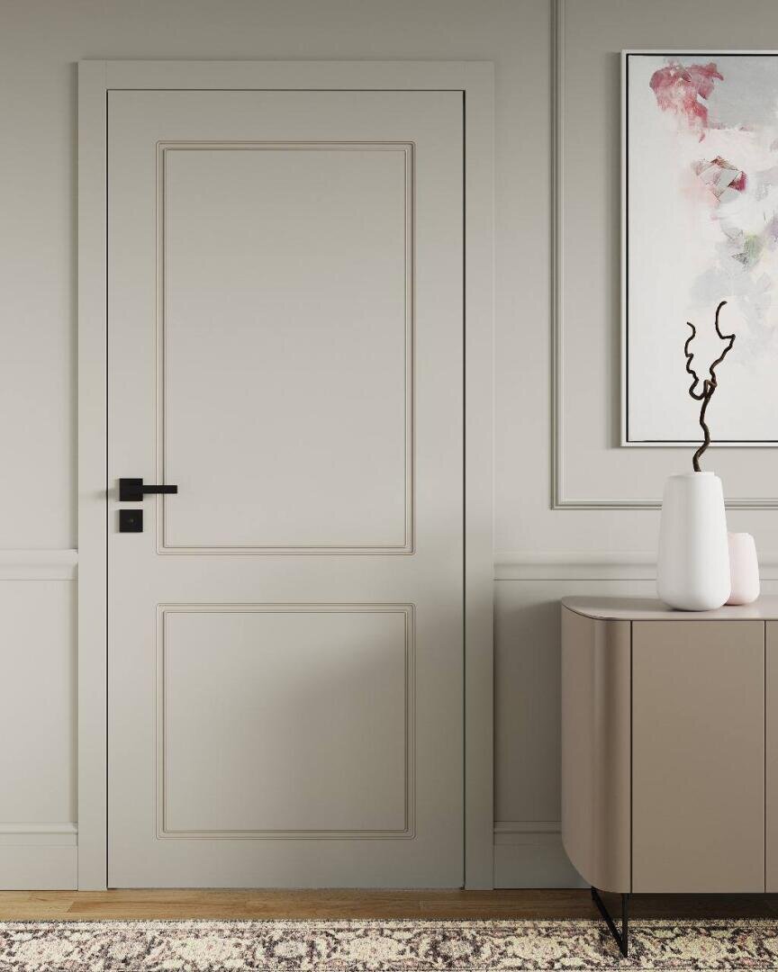 Eine moderne, beigefarbene Tür mit einem schwarzen Griff ist in eine helle Wand eingelassen. Daneben steht ein taupefarbenes Sideboard mit zwei weißen Vasen, eine davon mit einem verschlungenen Zweig, und darüber hängt ein abstraktes Gemälde. Auf dem Boden liegt ein gemusterter Teppich.