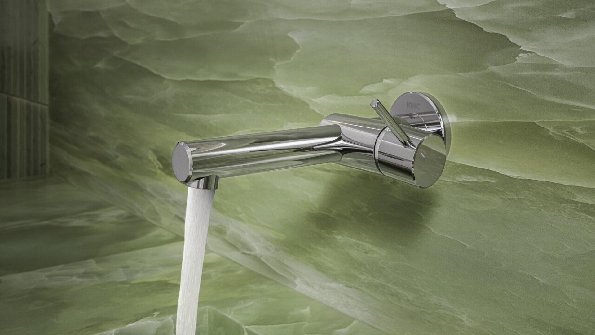 Un robinet mural moderne en chrome avec de l'eau s'écoulant du bec, posé sur un dosseret en marbre vert ou en pierre.