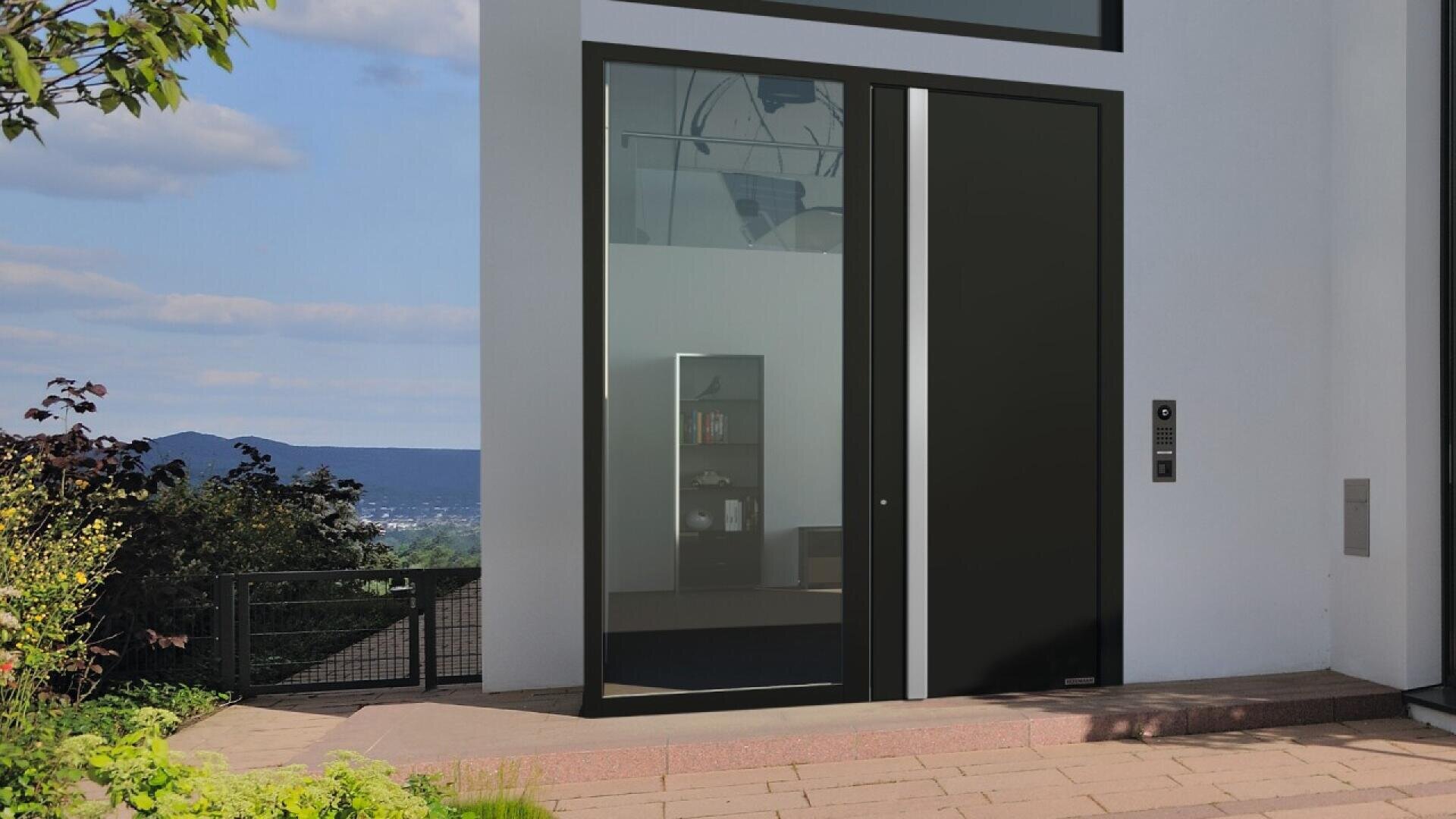 Une porte d'entrée moderne en verre et en noir sur un bâtiment blanc, avec une vue sur les arbres et les collines à l'extérieur, et un aperçu d'une bibliothèque intérieure à travers la vitre.
