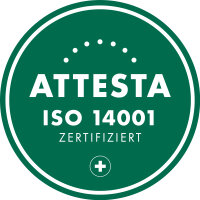 Insigne circulaire vert avec le texte blanc "ATTESTA ISO 14001 CERTIFIÉ" et une petite croix blanche dans un cercle au bas. Arc en pointillés au-dessus du texte principal.